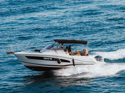The boat under way from the side, guests sitting in the cockpit under the bimini top