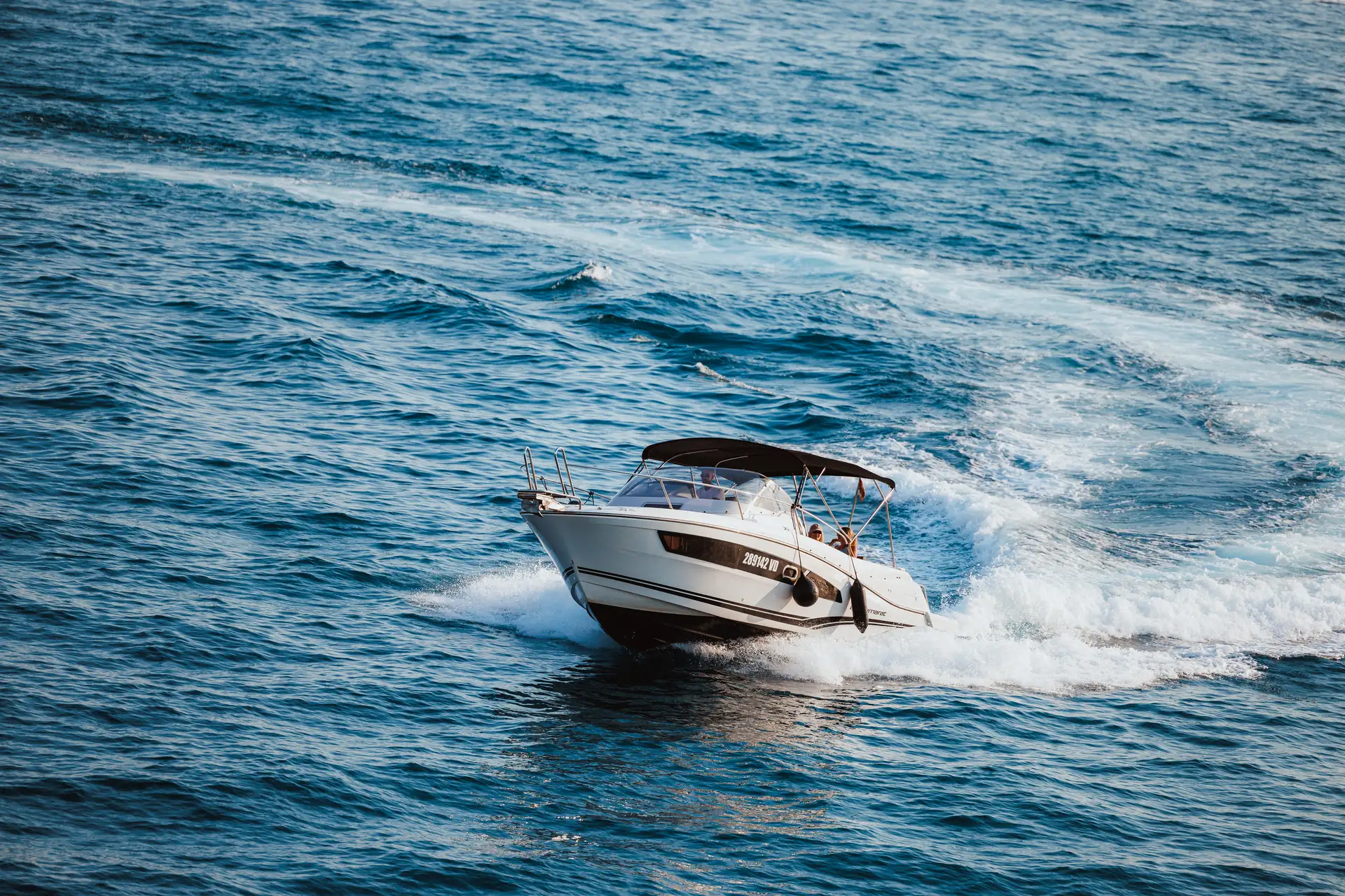 Our white motorboat speeding across open blue water and leaving a broad wake