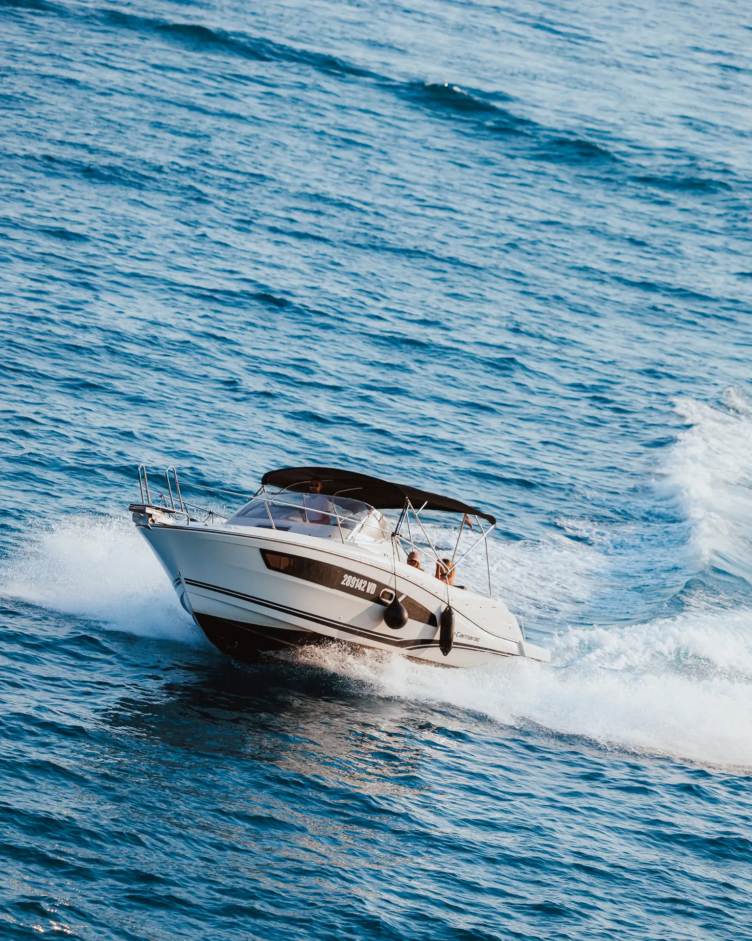 A white private motorboat speeding across the blue Adriatic Sea